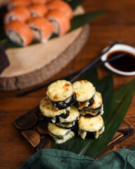 baked rolls lie on bamboo leaves on a wooden background. rolls - a dish of traditional Japanese cuisine made from rice with vinegar seasoning and various seafood