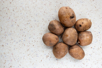 Fototapeta premium Group of potatoes on the white table. Taken at natural light falling from the window