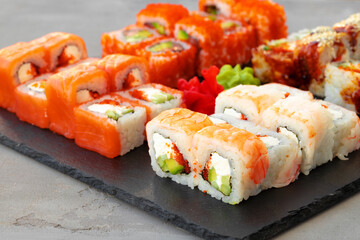 Set of various sushi rolls served on gray background