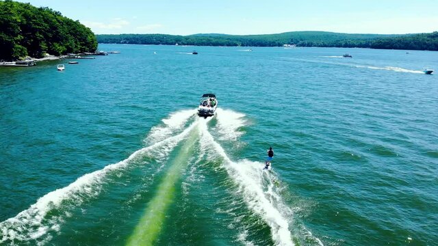 Tourist enjoying water skiing, tied behind high speed motor boat. Drone tracking footage. Aerial.