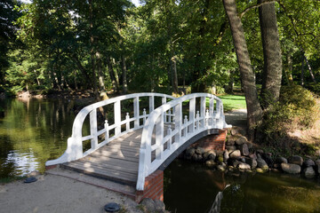 a simple white wooden bridge built across a narrow river