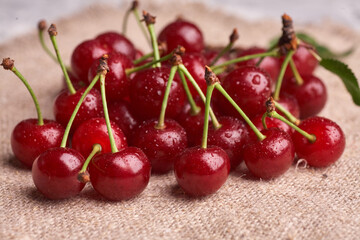 Bowl with red cherry on sackcloth background, top view