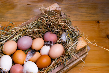 Easter eggs in wooden box, in nest from straw on wooden background