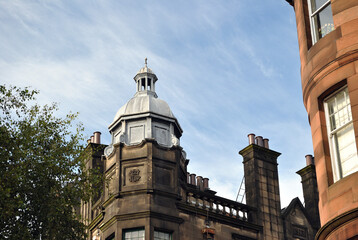 Fototapeta na wymiar Ornate Metal Cupola on Corner Of Stone Victorian Building against Blue Sky