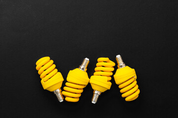 Yellow light bulbs on black background top view