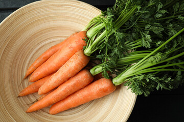 Bowl with fresh carrot on dark wooden background