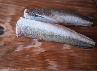 raw fish on a wooden board, healthy vegetarian food, frozen hake (Merluccius) on a kitchen board, fish cooking