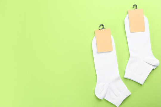 Soft cotton socks on light green background, flat lay. Space for text