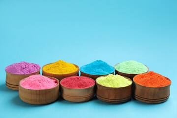 Colorful powders in bowls on light blue background, space for text. Holi festival celebration
