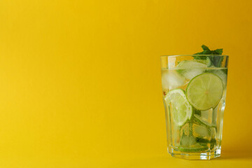 Glass of mojito cocktail on yellow background