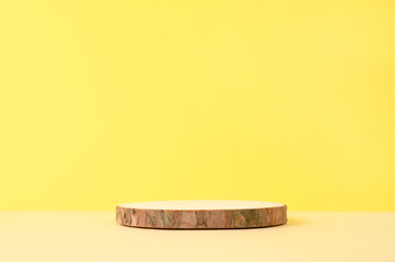 Round wooden podium on beige and yellow background for product.