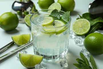 Glass of fresh mojito cocktail and ingredients on white background