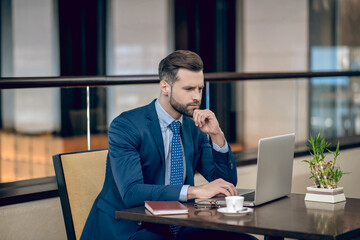 Fototapeta premium Young businessman in a nice suit working in the office and looking concentrated