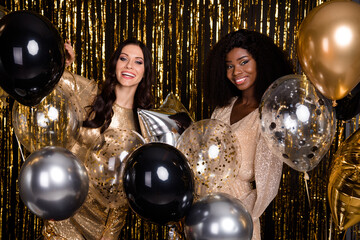 Photo of optimistic brunette ladies hold balloon wear nice dresses isolated on bright gold color background