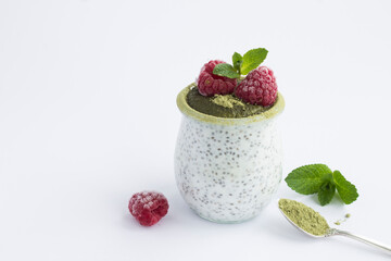 Chia seed pudding with raspberry and matcha tea in the glass jar on the white background. Close-up. Copy space.