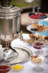 View of a round table with tea-ware from a traditional Russian samovar. Bakery, sweet food concept. Delicious pastries, jam and berries on the table. Birthday celebration. Children's holiday.