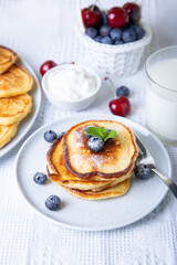 Cottage cheese pancakes (syrniki). Homemade cheesecakes from cottage cheese with sour cream, berries and milk. Traditional Russian dish. Close-up.