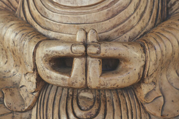 Wooden hands of the Buddha are folded in mudra.