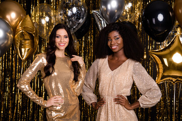 Photo of two charming pretty ladies posing hands hips balloon party wear glossy dresses isolated tinsel background © deagreez