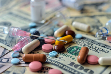 A lot of pills and capsules lie on the banknotes.