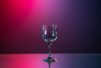 One glasse of red wine and bottle on the fantastic red-blue background