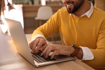 Man working with laptop at table in cafe, closeup