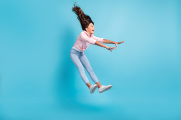 Full length photo of astonished carefree kid playing jumping falling open mouth isolated on blue...