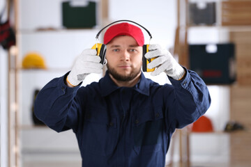 Worker holding safety headphones indoors, focus on hands. Hearing protection device