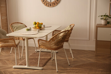 Stylish white dining table and wicker chairs in room. Interior design