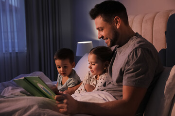 Father reading bedtime story to his children at home