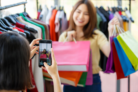 Blurred woman taking photo of girlfriend in shop