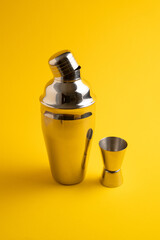 Cobbler shaker. Vertical image. Bar accessories. Traditional Shaker made from stainless steel. Yellow background