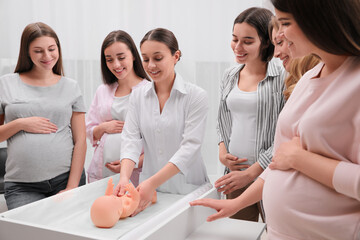 Pregnant women learning how to swaddle baby at courses for expectant mothers indoors