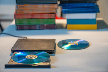 Compact stylish video player for CD and DVD disks with a pile of many TV series movie discs in background. - obrazy, fototapety, plakaty