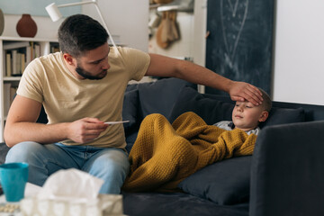 Fototapeta premium father measure temperature to his son. son has flue