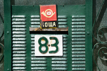 Old house’s metal aged door with mailbox and sign 83 number, urban concept, green door