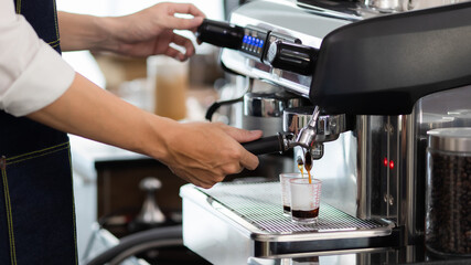 Close up hand. Making a cup of coffee in a coffee machine, the steam and the cup. Espresso maker machine with portafilter close up. Concept Coffee maker in cafe.