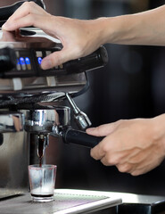 Fototapeta na wymiar Close up hand holding of making coffee with machine in cafe. Professional modern espresso coffee machine pours hot drink into the cup. Concept coffee in cafe.