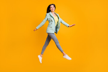Fototapeta na wymiar Full size photo of young attractive lovely pretty smiling girl jumping wear green blazer isolated on yellow color background