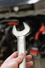 hand of a caucasian man holding a wrench with decision, prepared to fix a car