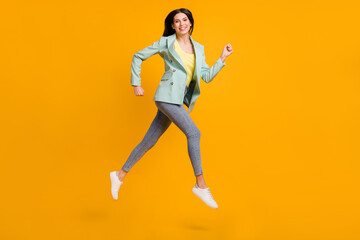 Fototapeta na wymiar Full length photo of cute charming young woman wear teal blazer jumping running isolated yellow color background