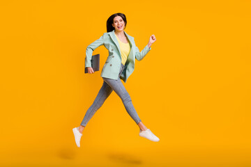 Fototapeta na wymiar Full size photo of young lovely pretty smiling cheerful girl run jump with laptop in hand isolated on yellow color background