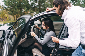 Girl driving a car, driver. An attractive girl learns to drive a car, her young boyfriend helps her...