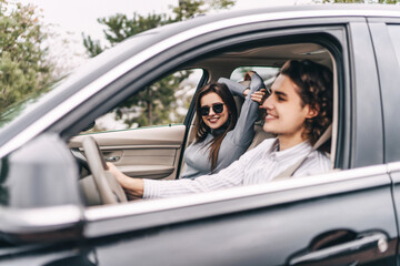 Enjoy traveling, driving a car. Young smiling couple, beautiful girl looks at the camera and smiles