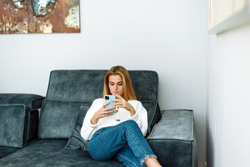 Relax on the couch at home. Lifestyle. Attractive woman using smart phone while sitting on the sofa