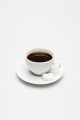 cup of prepared coffee and sugar cubes on saucer on white