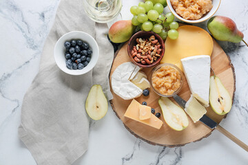 Tasty pear jam with different cheeses and nuts on white background
