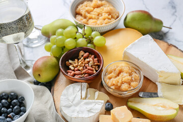 Tasty pear jam with different cheeses and nuts on table