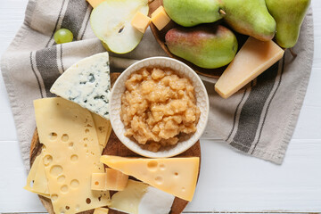 Tasty pear jam with different cheeses on white wooden background