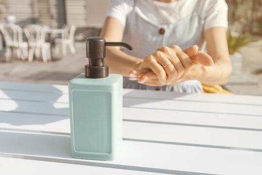 woman visitor to the cafe washes her hands with a dispenser with a disinfectant and sanitizer. Concept of the coronavirus pandemic and misophobia